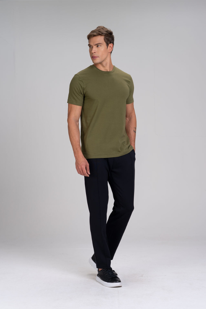 Homem de corpo inteiro vestindo camiseta masculina verde em algodão duplo egípcio Urbô, calça escura e tênis.