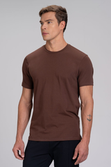 Homem de perfil vestindo camiseta masculina marrom em algodão duplo egípcio Urbô, com tatuagem de âncora no braço.